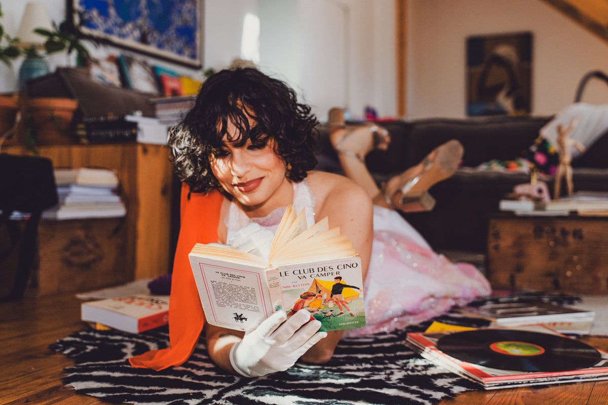 Mariée arty allongée sur un tapis, lisant un livre, avec un voile orange sanguine CANEZAN
