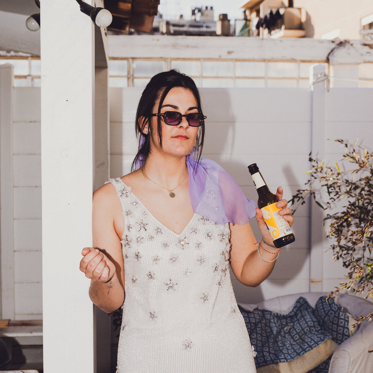 Mariée chill en lunettes de soleil, voile lilas CANEZAN sur les épaules, une bière à la main sur une terrasse